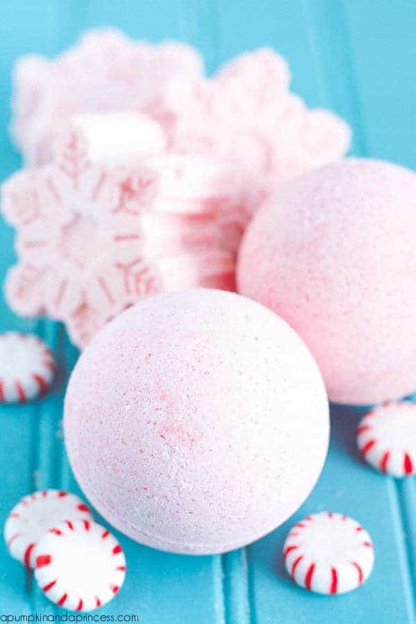 pale pink bath bombs surrounded by peppermint sweets and large pink bath bomb snowflakes