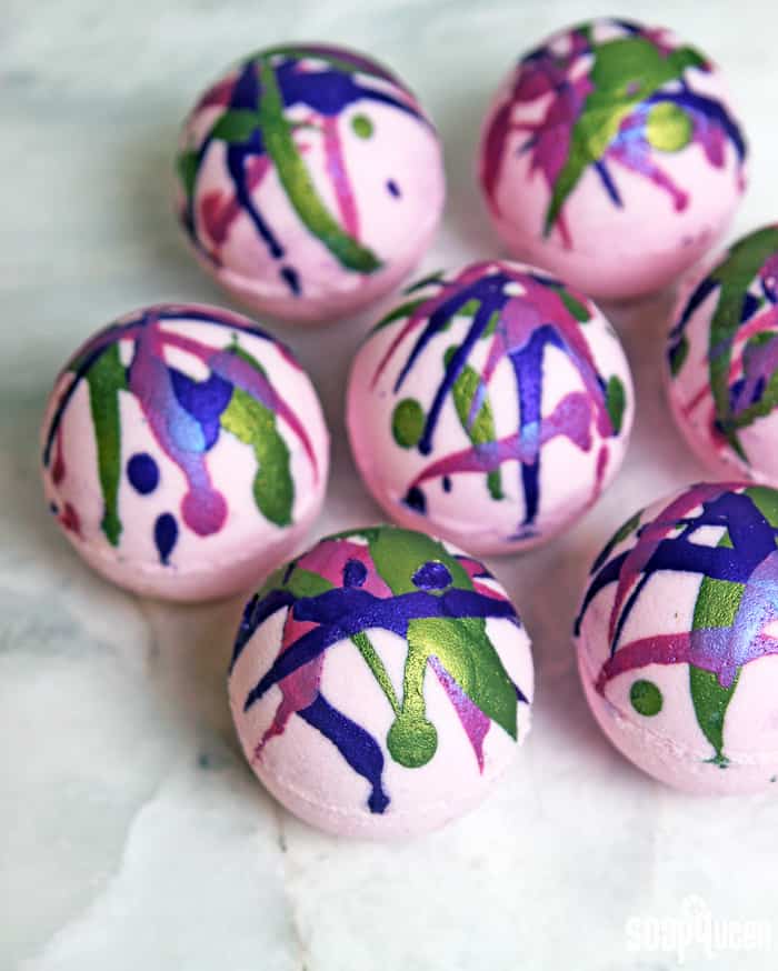 painted pink bath bombs with purple, blue, and green stripes