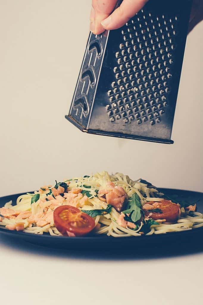 Grating cheese onto spaghetti dish