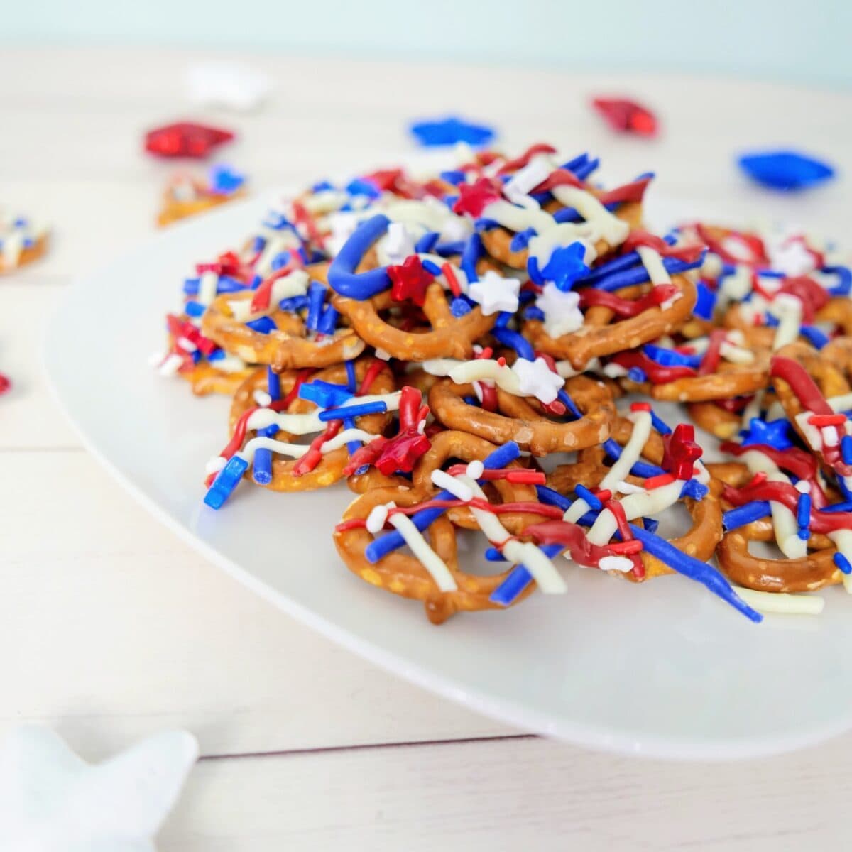 Red, white, and blue chocolate-covered patriotic pretzels on a plate, perfect for a 4th of July dessert.