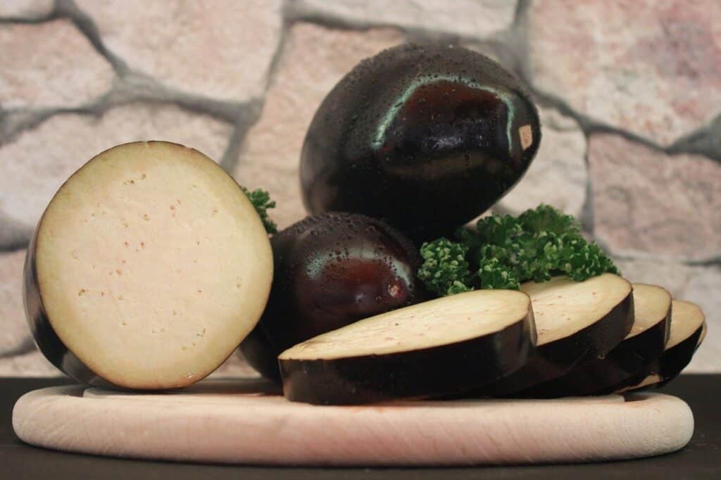 Sliced aubergine with herbs on a wooden chopping board