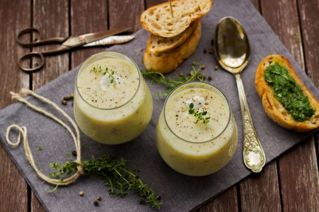 Title image for 10 Easy Ways To Create More Interesting Soup Recipes In Fall & Winter - two soup portions served in cups with bread