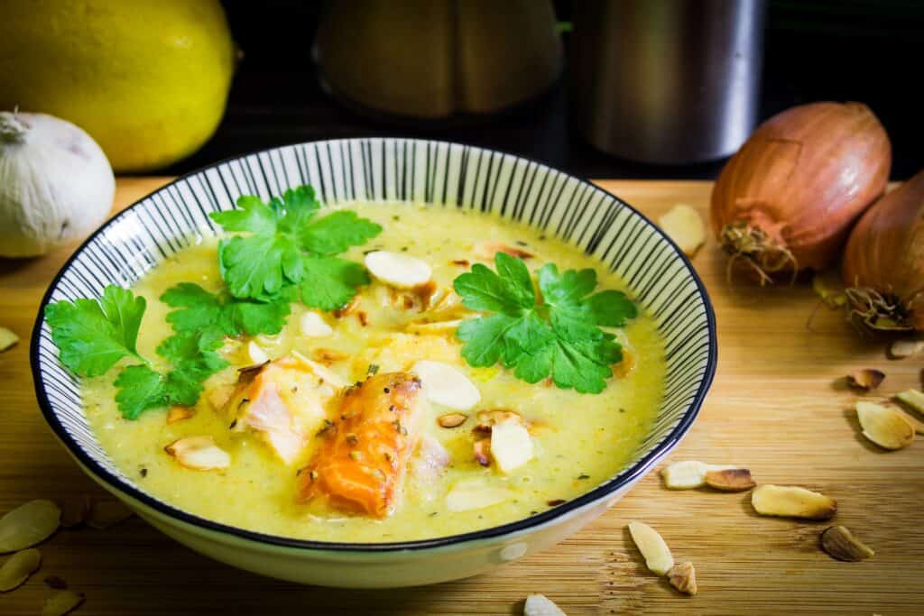 Thin soup with chunky meats and vegetables and topped with herbs