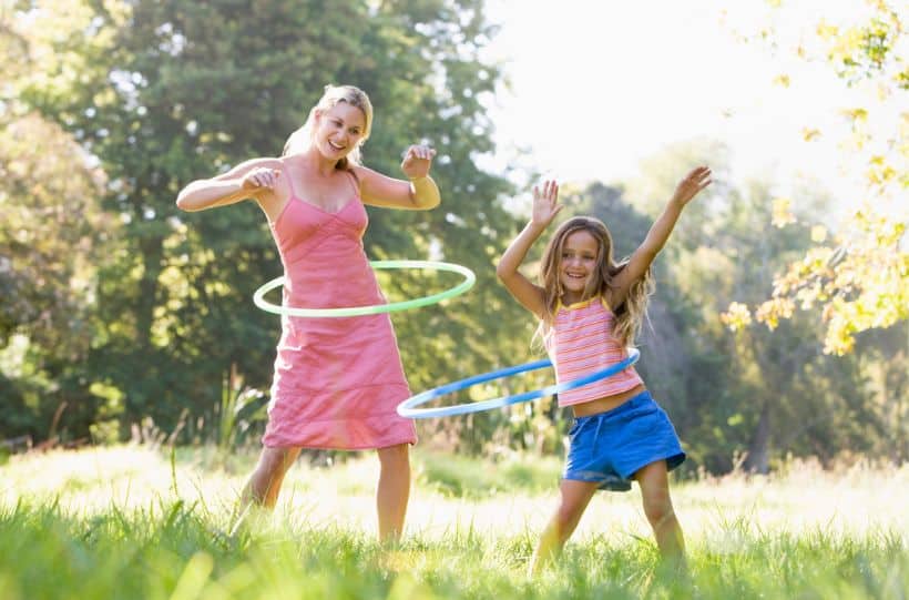 Woman and young girl outdoors using hula hoops