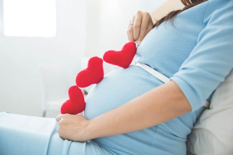 Asian young pregnant woman put heart shape accessories in her tu