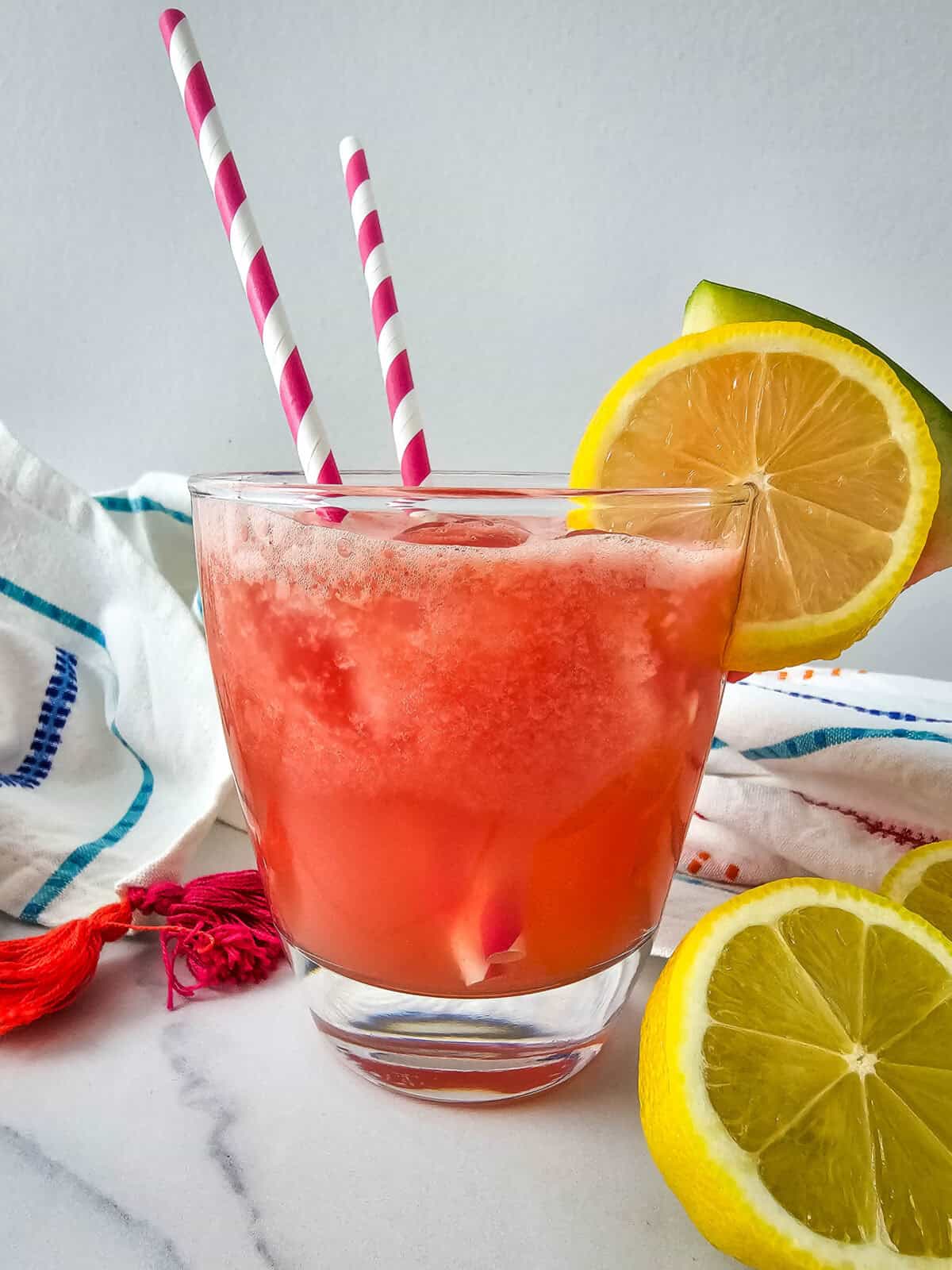 Refreshing watermelon lemonade cocktail served with ice and garnished with lemon slices.